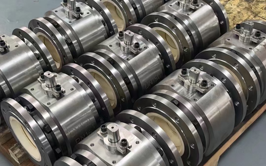 Finished stainless steel flanged ball valves lined up on a wooden pallet in a workshop, with DN150 and PN16 markings visible on the bodies